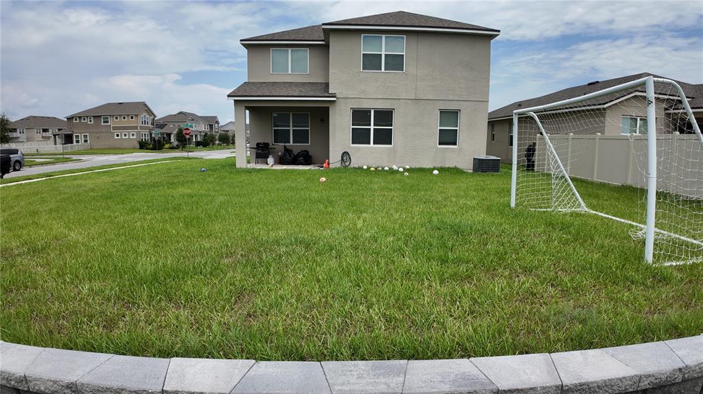 A two-story house with a backyard, a soccer goal, and a stone retaining wall — 2436 BLOWING BREEZE AVENUE, KISSIMMEE, FL