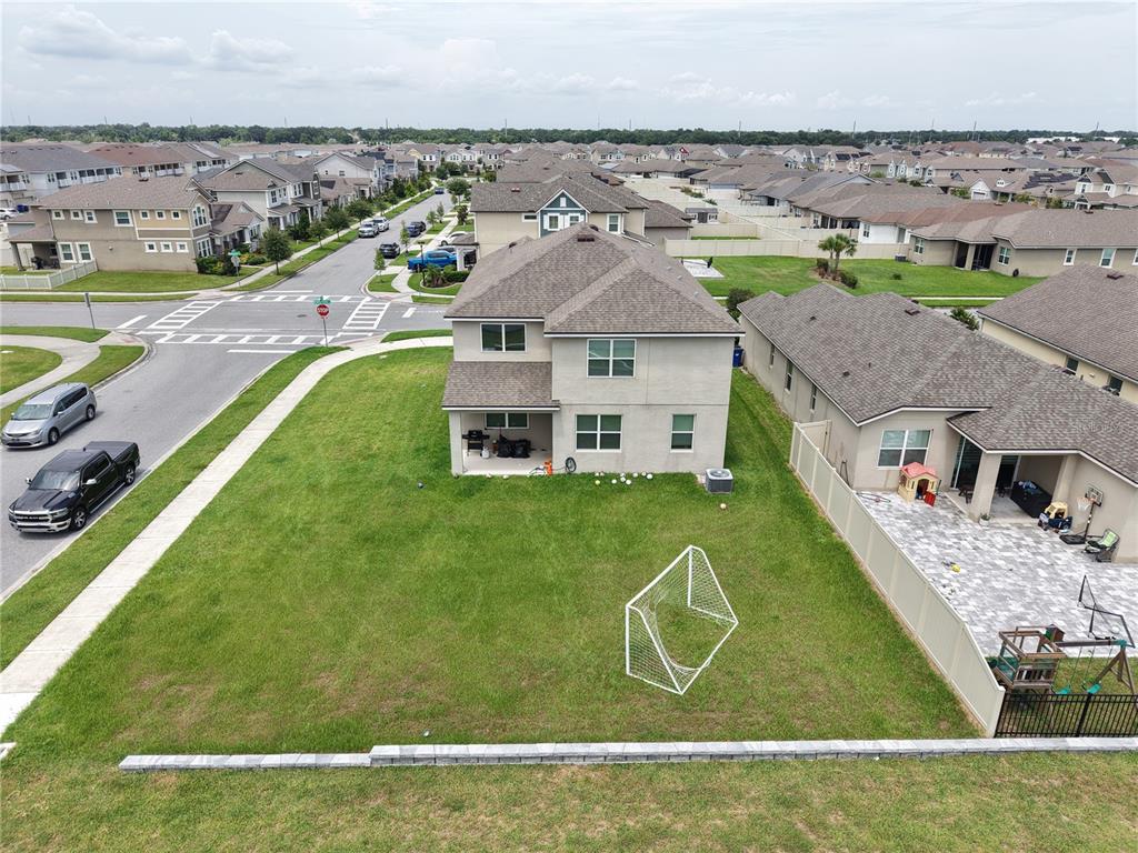 An aerial view shows a two-story house with a backyard, a soccer goal, and patio — 2436 BLOWING BREEZE AVENUE, KISSIMMEE, FL