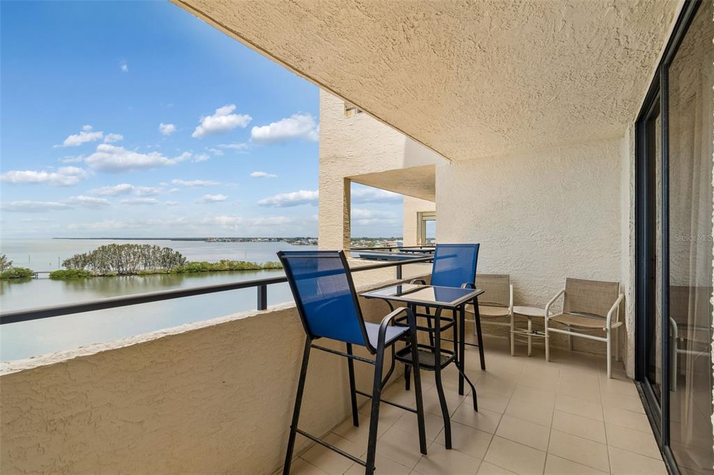 A balcony with a table and chairs overlooks a body of water and mangroves — 5915 SEA RANCH DRIVE UNIT 611, HUDSON, FL
