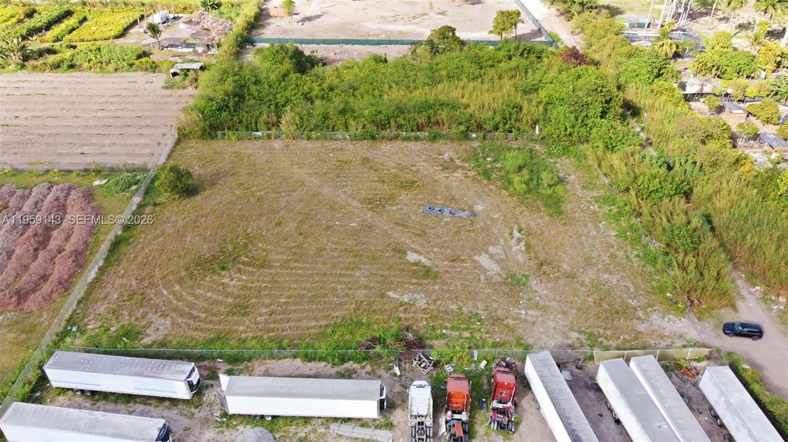 An aerial view shows a rectangular vacant lot bordered by a fence and parked trailers — 160XX SW 207TH AVE, Miami FL 33187, MIAMI, FL