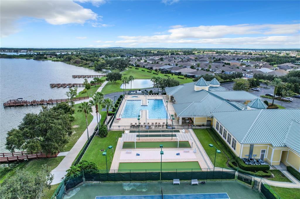 An aerial view shows a community clubhouse with a pool, sports courts, and a lake — 4019 CARTERET DRIVE, WINTER HAVEN, FL