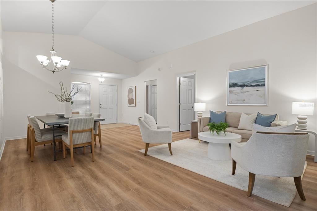 A bright, open-concept living and dining area features light wood flooring and vaulted ceilings — 4019 CARTERET DRIVE, WINTER HAVEN, FL