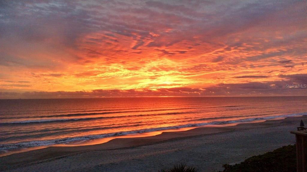 A view of a sandy beach and ocean under a vibrant orange sunset sky — 586 140TH AVENUE E UNIT 2, MADEIRA BEACH, FL