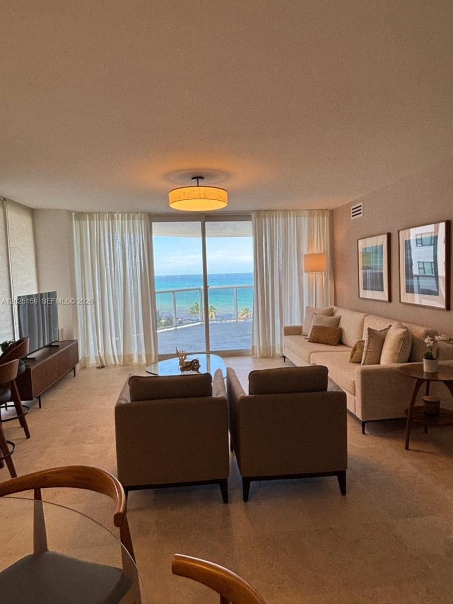 A living room features a beige sofa, two armchairs, and a balcony overlooking the ocean — 6301 Collins Ave # 908, Miami Beach FL 33141, MIAMI BEACH, FL