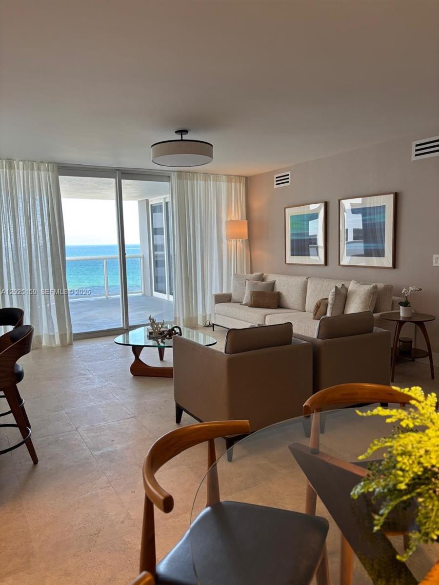 A living room features a beige sofa, two armchairs, and a balcony overlooking the ocean — 6301 Collins Ave # 908, Miami Beach FL 33141, MIAMI BEACH, FL