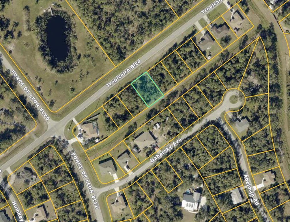 This is an aerial map showing a vacant lot highlighted in blue near residential streets — TROPICAIRE BOULEVARD, NORTH PORT, FL