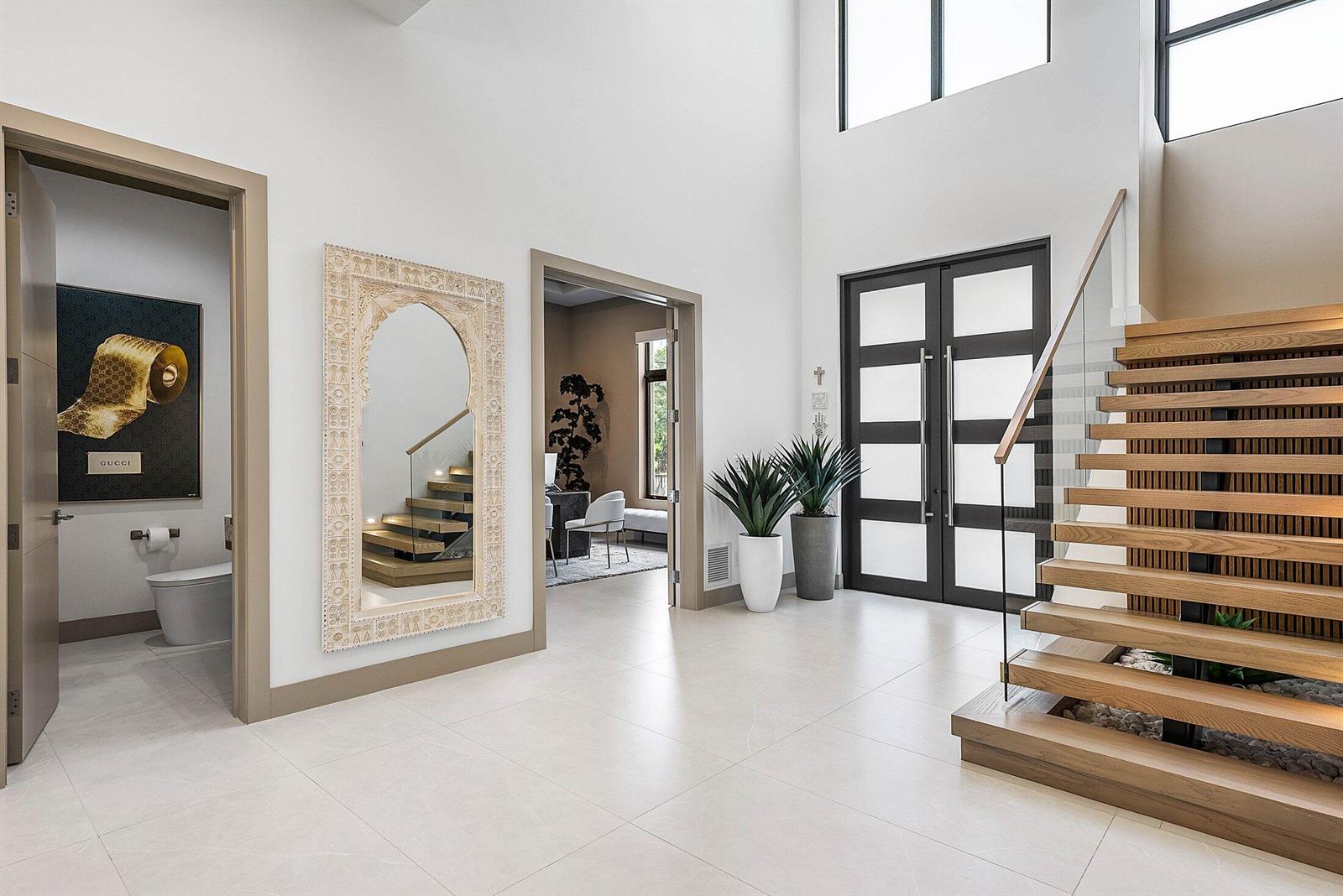 A bright foyer features a floating wooden staircase, a large ornate mirror, and a powder room — 499 NE 4th Street, Boca Raton FL 33432, BOCA RATON, FL