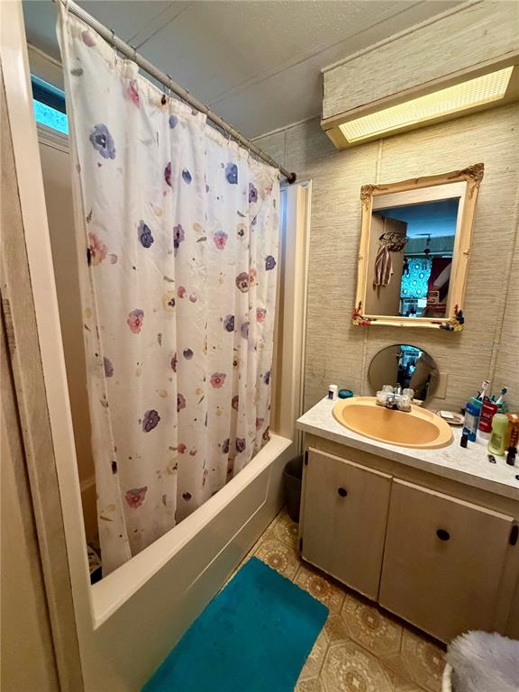 A bathroom features a floral shower curtain, a tan sink, and a framed wall mirror — 11710 NE 222ND LANE, FORT MC COY, FL