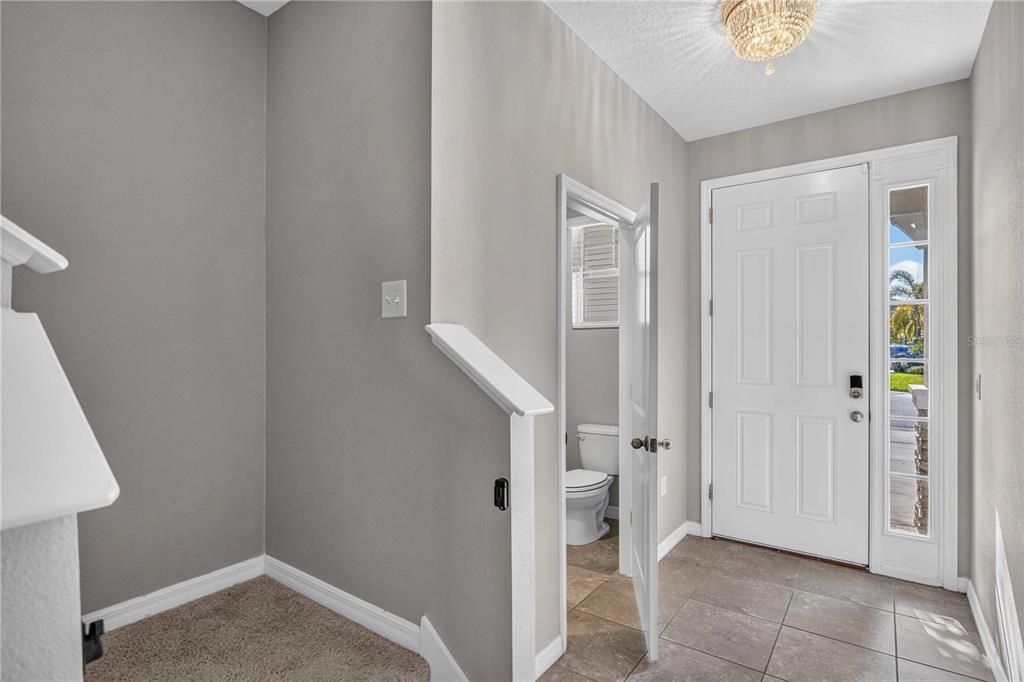 An entryway features tile flooring, a white front door, and an adjacent half bathroom — 2683 MIDNIGHT PEARL DRIVE, SARASOTA, FL