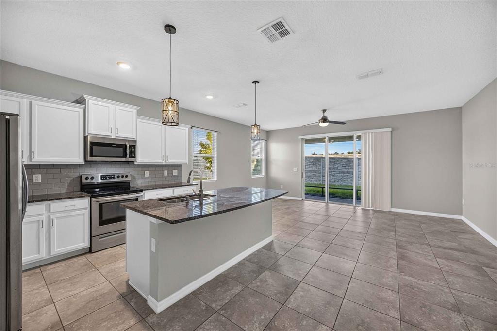 A kitchen with white cabinets, dark countertops, and a center island opens to a living area — 2683 MIDNIGHT PEARL DRIVE, SARASOTA, FL