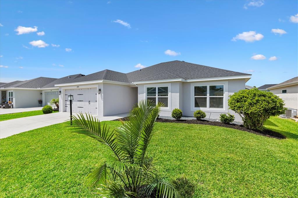 A single-story house with a gray roof, light-colored stucco exterior, and a manicured front lawn — 1574 ROWELL STREET, THE VILLAGES, FL