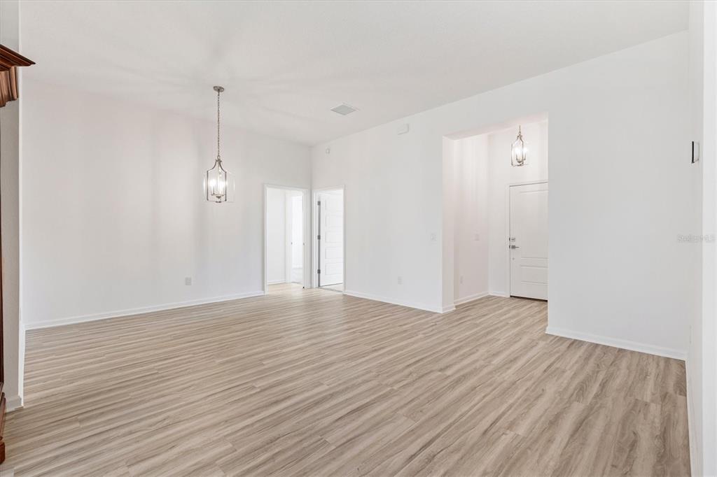 An empty room with light wood-look flooring, white walls, and two hanging pendant lights — 1574 ROWELL STREET, THE VILLAGES, FL
