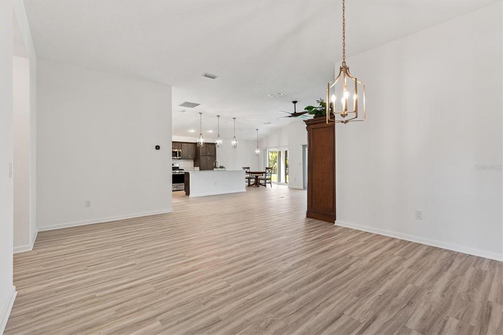An open-concept living and dining area features light wood-look flooring and a modern pendant light — 1574 ROWELL STREET, THE VILLAGES, FL