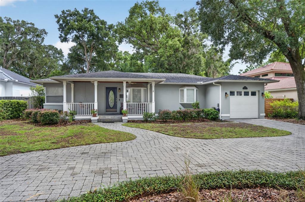 A single-story gray house features a front porch, a paved driveway, and mature trees — 150 E READING WAY, WINTER PARK, FL