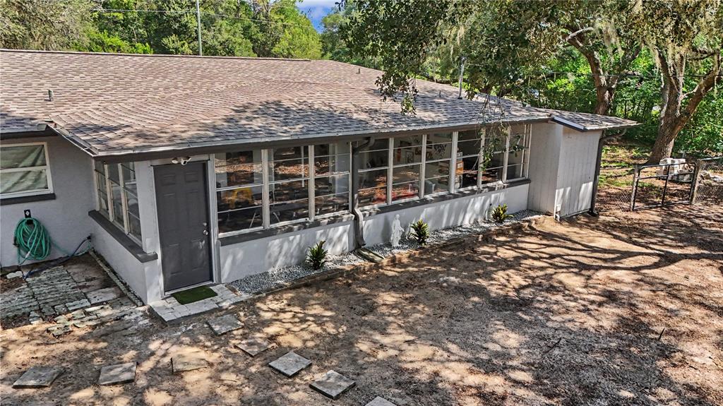 An exterior view of a house with a gray door, large windows, and a yard — 20260 SW 80TH PLACE ROAD, DUNNELLON, FL