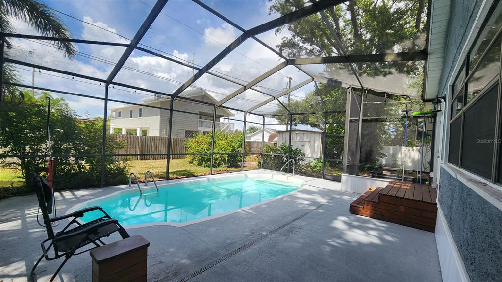 A screened-in patio features a swimming pool, concrete deck, and wooden steps — 155 69TH AVENUE N, ST PETERSBURG, FL