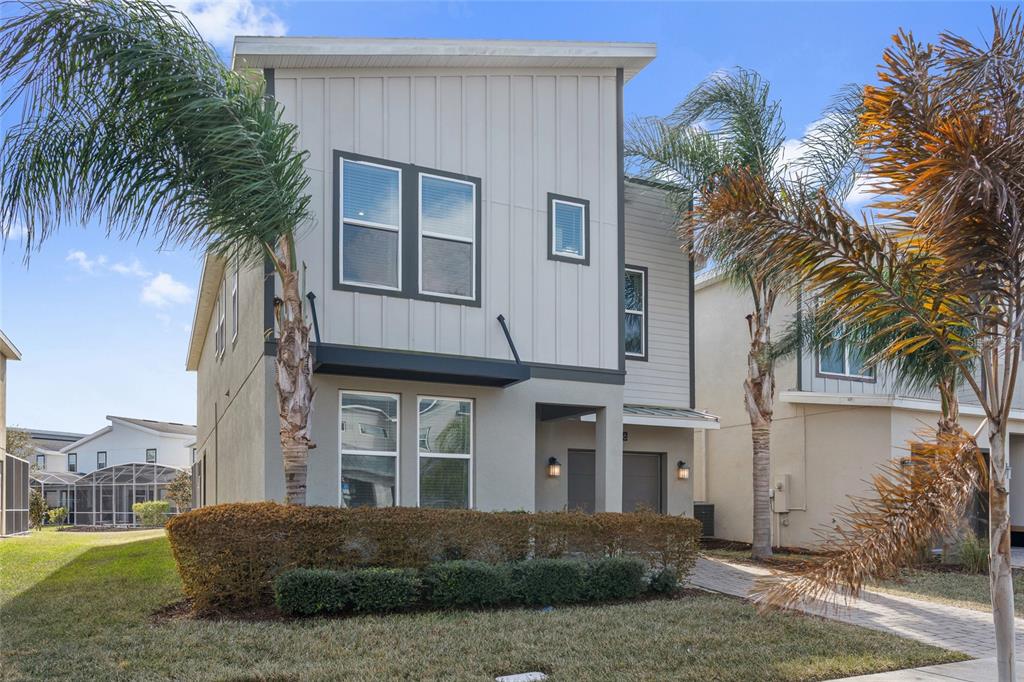A two-story modern house with vertical siding, a small front porch, and palm trees — 8986 CABOT CLIFFS DRIVE, DAVENPORT, FL