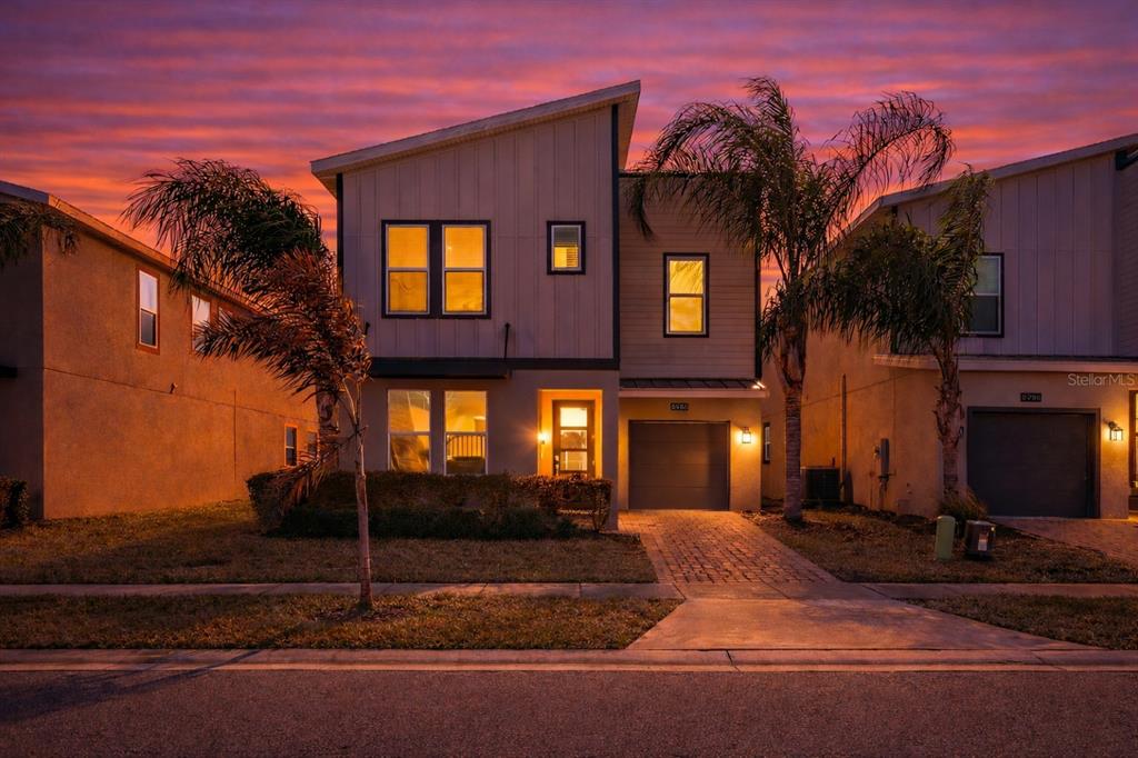 A two-story modern house with a garage and palm trees at sunset — 8986 CABOT CLIFFS DRIVE, DAVENPORT, FL
