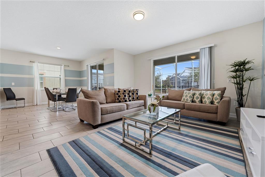 A living room with tile floors, two beige sofas, a glass coffee table, and striped rug — 8986 CABOT CLIFFS DRIVE, DAVENPORT, FL