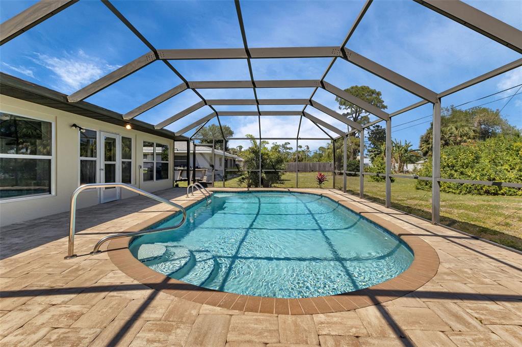 A screened-in swimming pool with a paver patio and a metal pool enclosure — 745 COLUMBIA STREET, PORT CHARLOTTE, FL