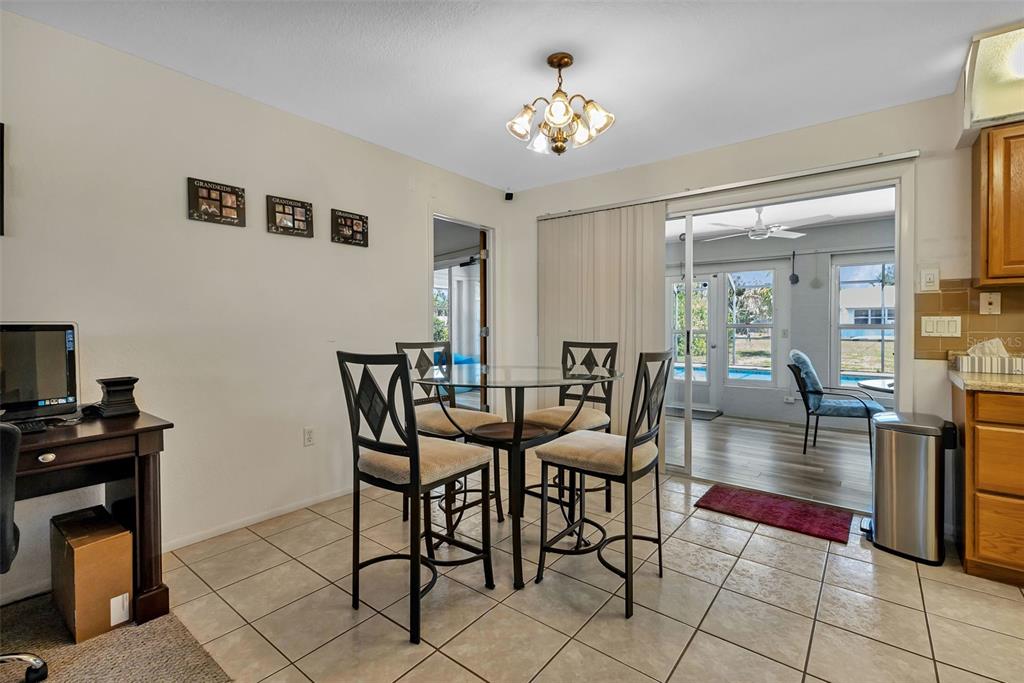 A dining area with a glass table, four chairs, tile flooring, and a sliding glass door — 745 COLUMBIA STREET, PORT CHARLOTTE, FL