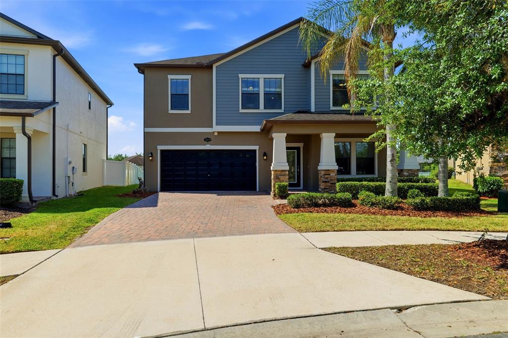 A two-story house with a brick driveway, dark garage door, and blue siding — 19419 PADDOCK VIEW DRIVE, TAMPA, FL