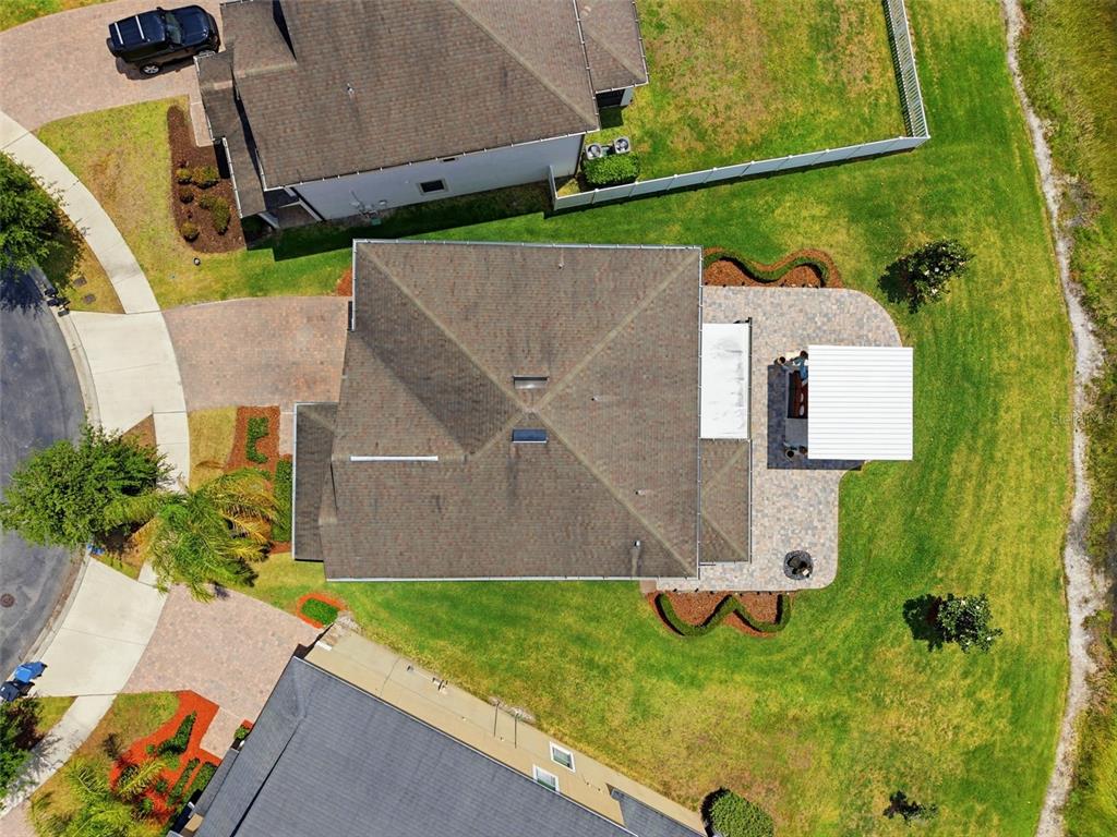 An aerial view shows a house with a paved patio, pergola, and surrounding lawn — 19419 PADDOCK VIEW DRIVE, TAMPA, FL