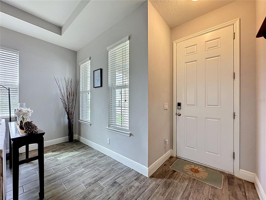 An entryway features gray walls, wood-look tile flooring, two windows with blinds, and a white door — 105 ABERDEEN STREET, DAVENPORT, FL