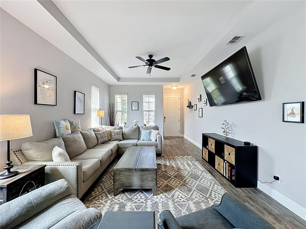 A living room features a sectional sofa, a coffee table, and a wall-mounted television — 105 ABERDEEN STREET, DAVENPORT, FL