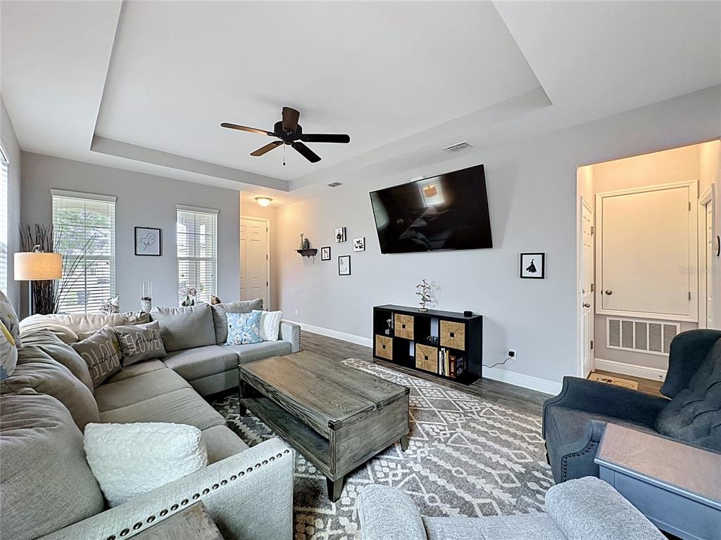 A living room features a sectional sofa, a coffee table, and a wall-mounted television — 105 ABERDEEN STREET, DAVENPORT, FL