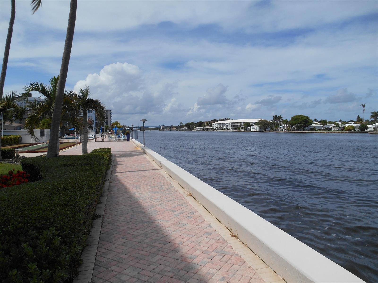 A paved walkway runs alongside a canal with palm trees and buildings in the background — 2016 S Federal Highway # 204, Boynton Beach FL 33435, BOYNTON BEACH, FL