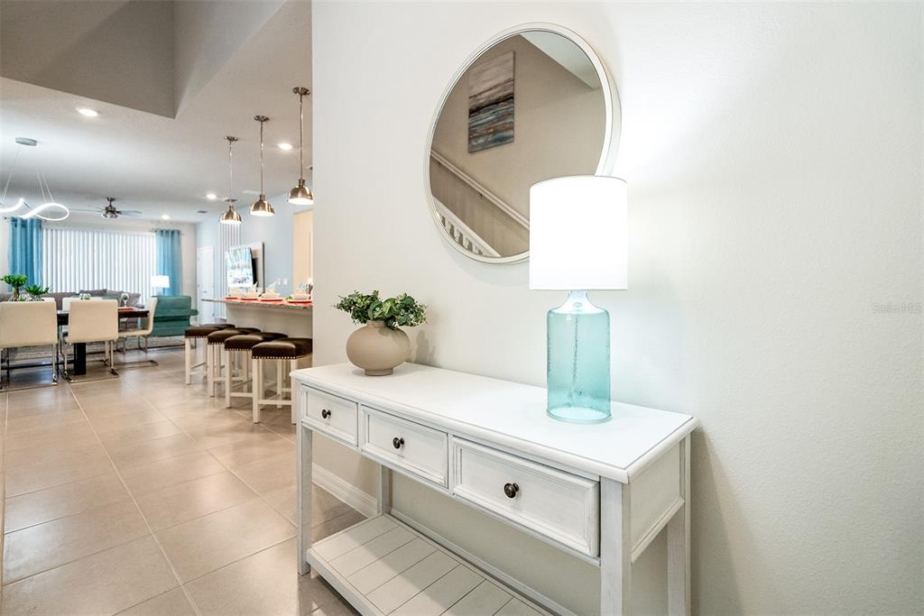 A white console table with a lamp and mirror sits in a bright home entryway — 4051 LANA AVENUE, DAVENPORT, FL