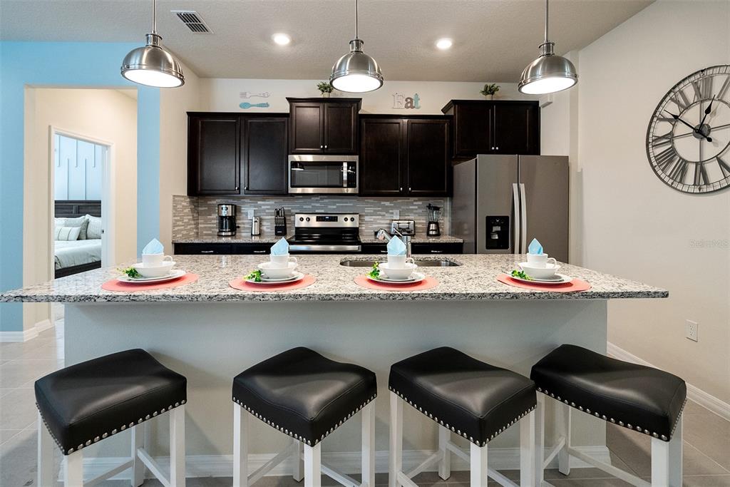 A kitchen features dark wood cabinets, granite countertops, a breakfast bar, and four stools — 4051 LANA AVENUE, DAVENPORT, FL
