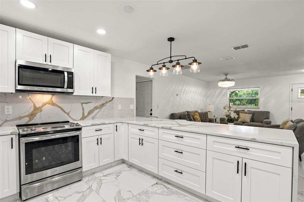 A modern kitchen with white cabinets, marble countertops, and a stainless steel stove — 2629 TELSTAR AVENUE, ORLANDO, FL