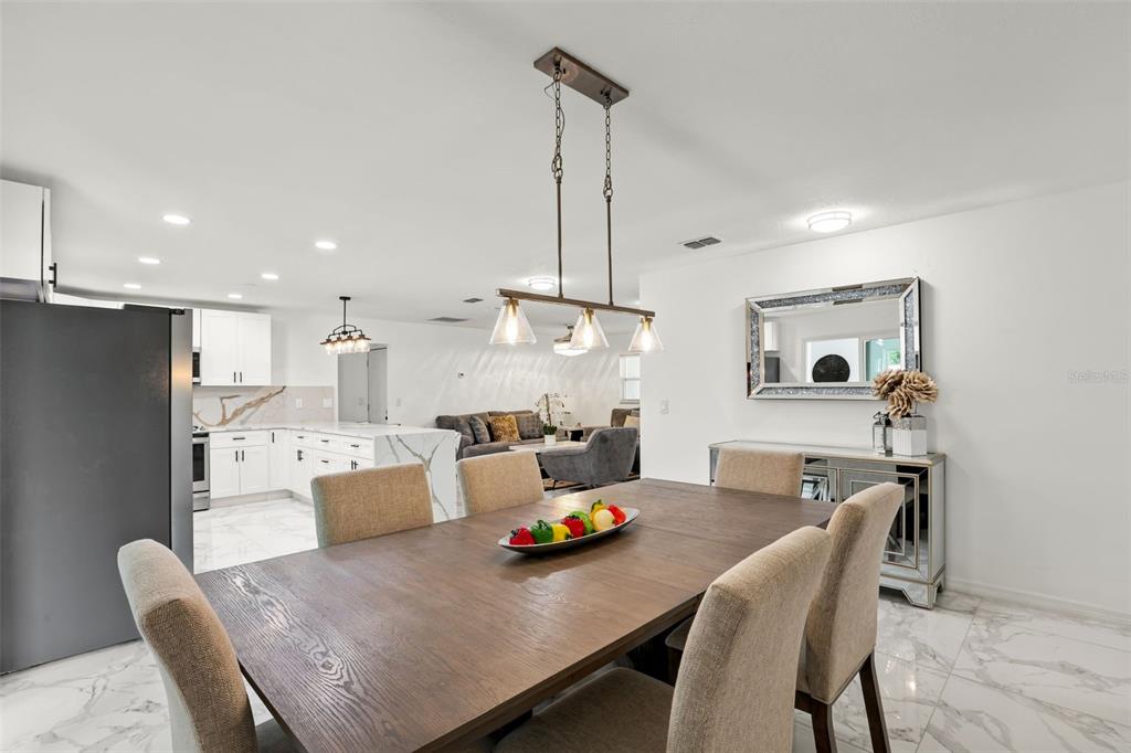 A dining area with a wooden table and chairs opens into a modern white kitchen — 2629 TELSTAR AVENUE, ORLANDO, FL
