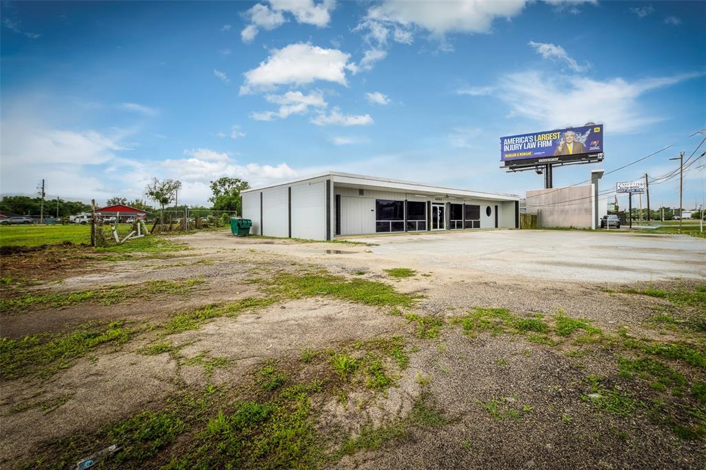 A single-story commercial building with a large parking lot and a billboard on top — 6464 E COLONIAL DRIVE, ORLANDO, FL