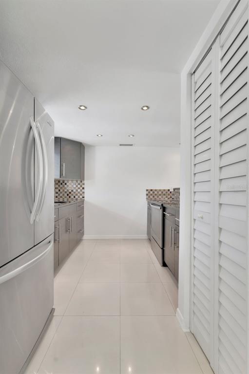 A galley kitchen features stainless steel appliances, dark grey cabinetry, and light-colored tile flooring — 592 100TH AVENUE N UNIT 201, ST PETERSBURG, FL