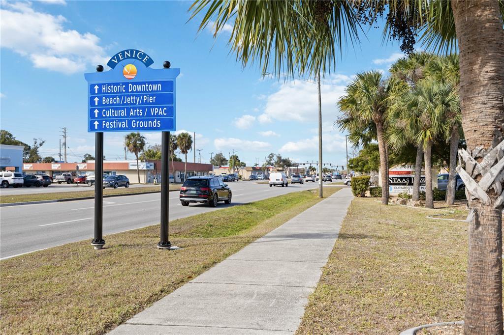 An aerial view shows a vacant, tree-covered lot outlined in red between two commercial buildings — 841 E VENICE AVENUE, VENICE, FL