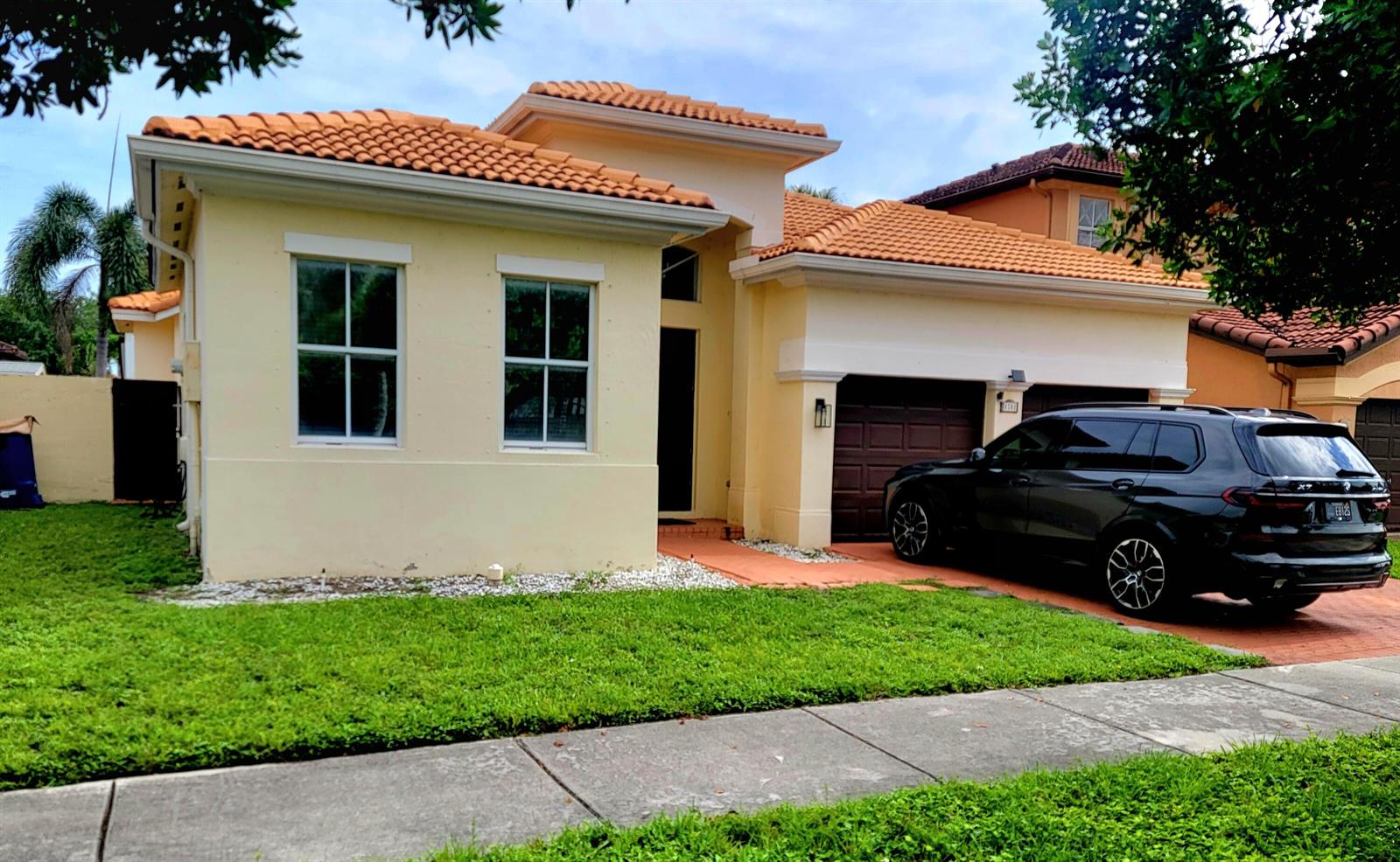A single-story house with a light yellow exterior, orange tile roof, and a black SUV — 8781 NW 178th Street, Hialeah FL 33018, HIALEAH, FL