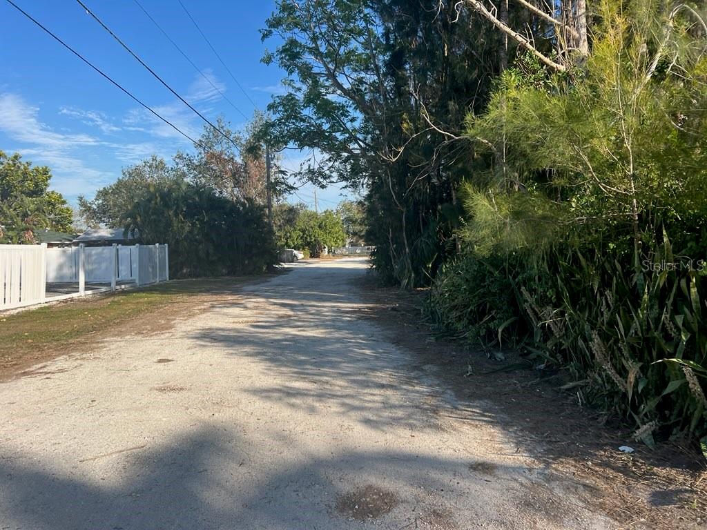 A gravel road leads through a residential area lined with trees and a white fence — 4122 N LOCKWOOD RIDGE ROAD, SARASOTA, FL