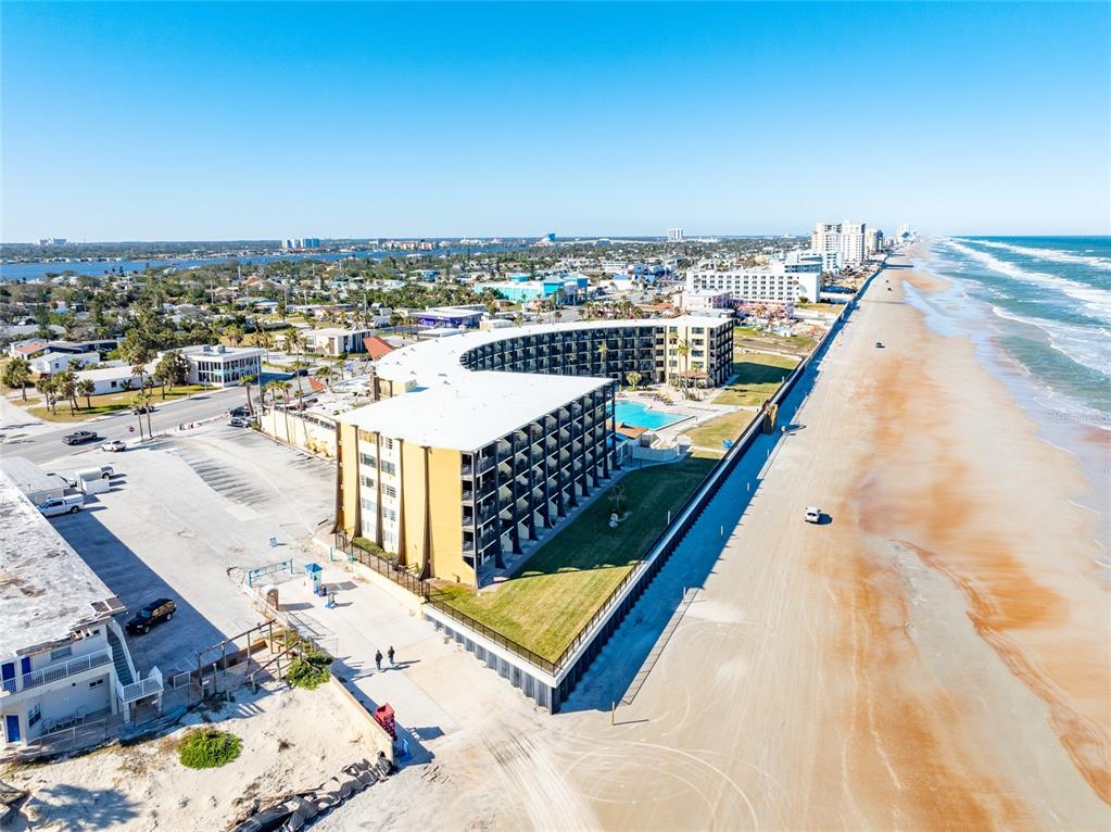An aerial view shows a multi-story hotel building situated directly on a sandy beach — 2301 S ATLANTIC AVENUE UNIT 127, DAYTONA BEACH, FL