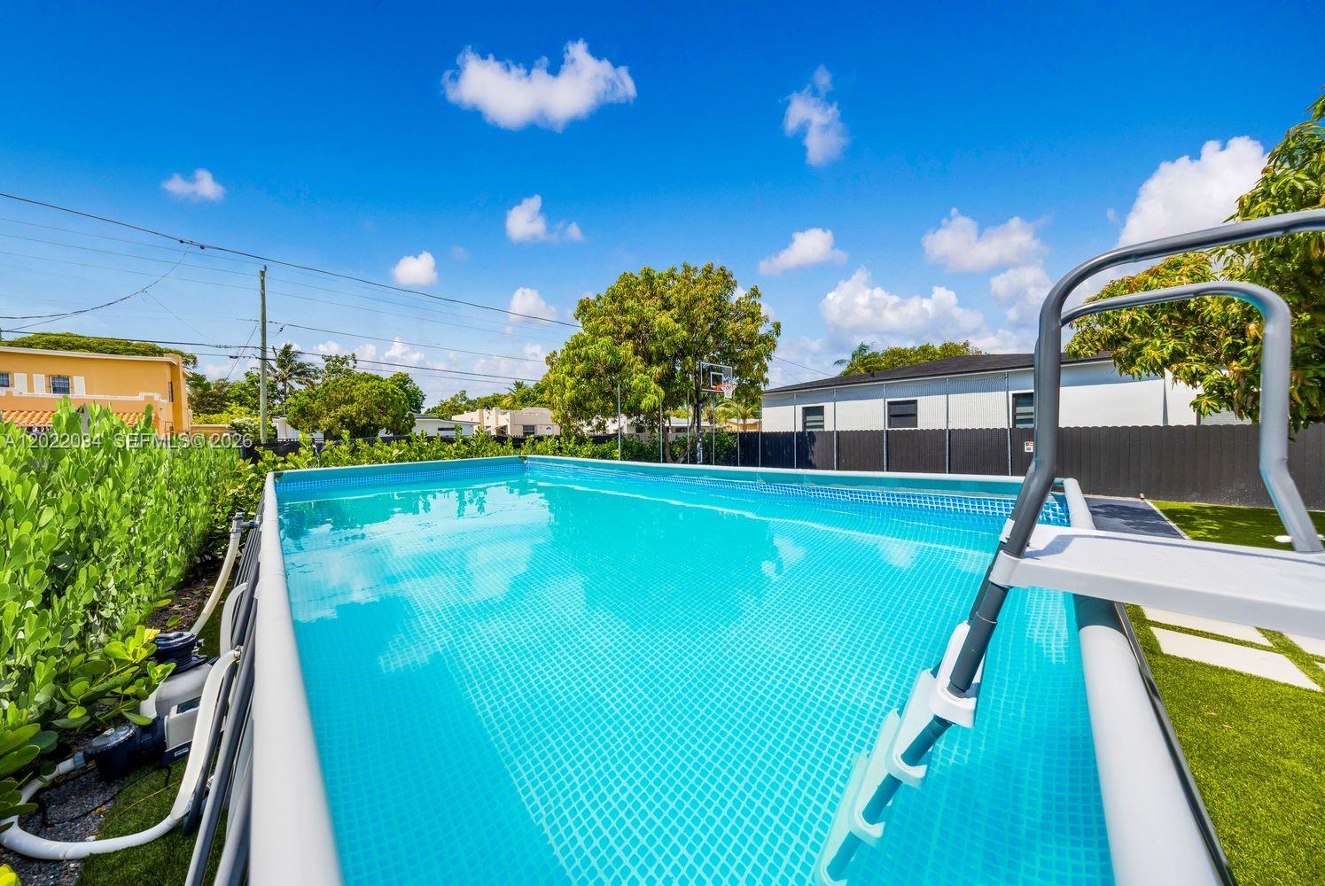 An above-ground swimming pool with a ladder sits in a backyard with artificial turf — 111 NW 53rd St, Miami FL 33127, MIAMI, FL