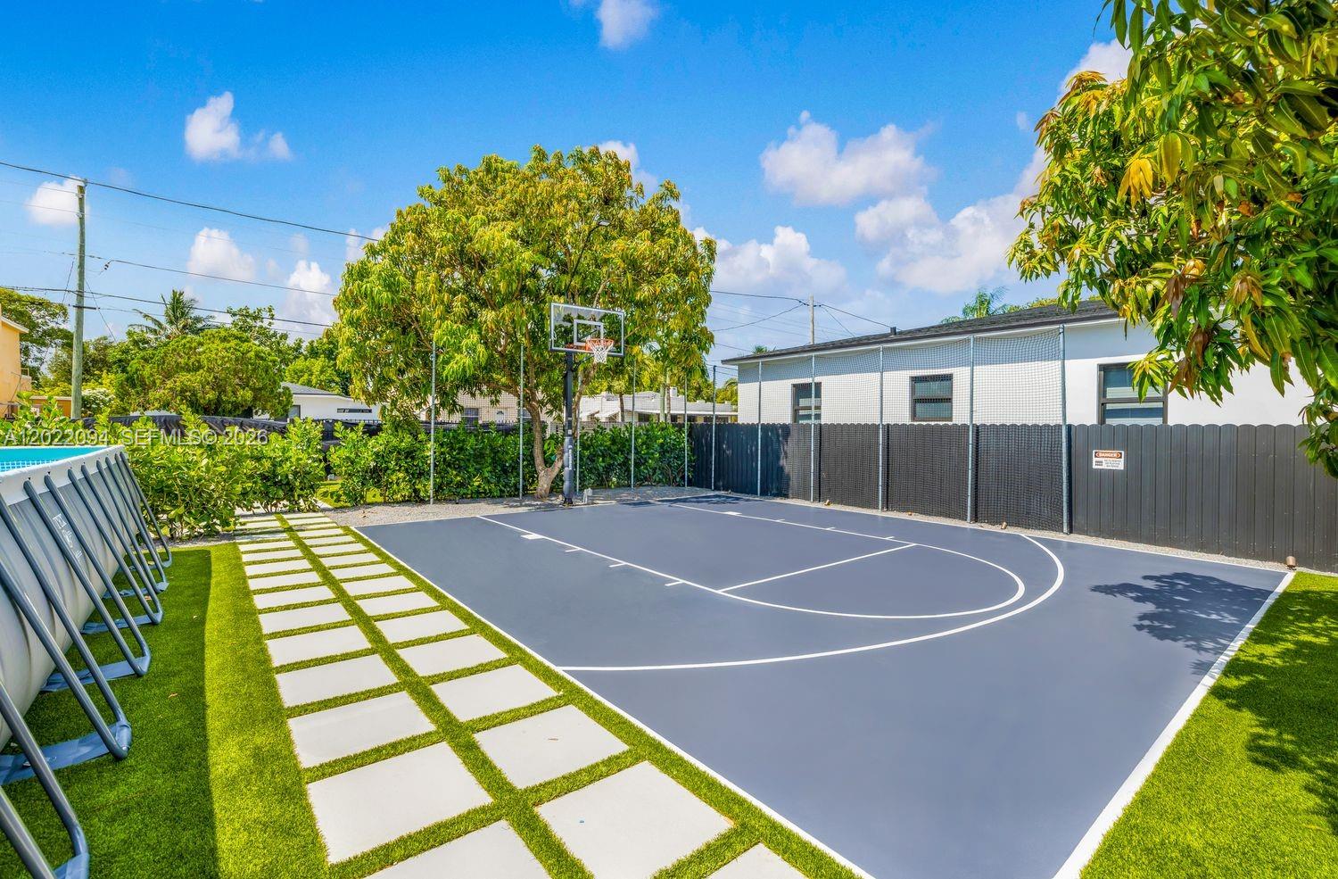 A backyard features a blue basketball court with white lines and a surrounding black fence — 111 NW 53rd St, Miami FL 33127, MIAMI, FL