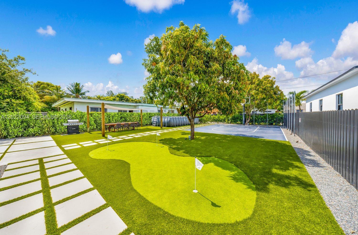 A backyard features a putting green, a basketball court, and a large tree — 111 NW 53rd St, Miami FL 33127, MIAMI, FL