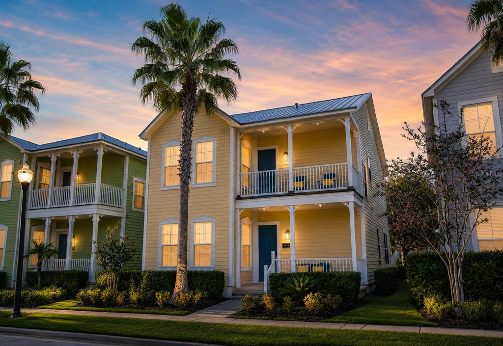 A yellow two-story house with double porches and a palm tree at sunset — 1549 FAIRVIEW CIRCLE, REUNION, FL