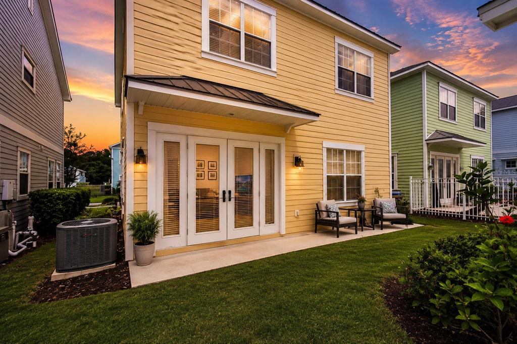 The exterior of a yellow two-story house features a patio with chairs and French doors — 1549 FAIRVIEW CIRCLE, REUNION, FL