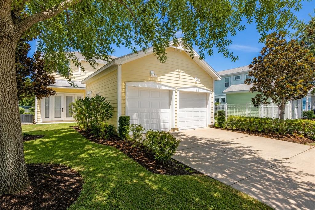 A yellow detached two-car garage sits next to a house with a green exterior — 1549 FAIRVIEW CIRCLE, REUNION, FL