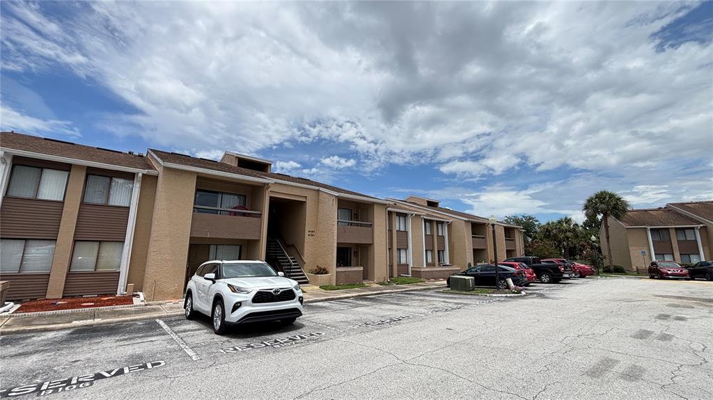 A white SUV is parked in front of a two-story tan apartment building — 5169 VINELAND ROAD UNIT B208, ORLANDO, FL