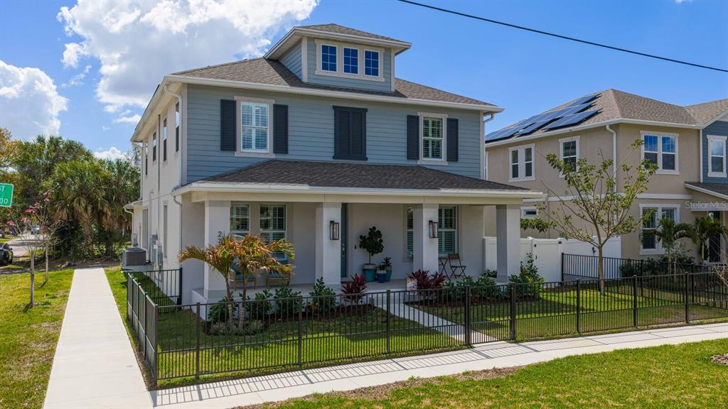 A two-story blue house with a front porch and a black metal fence — 2702 W CASS STREET, TAMPA, FL