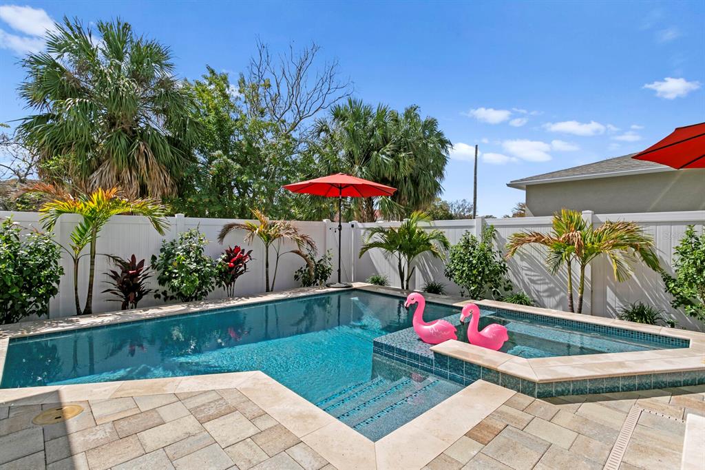 A backyard swimming pool with a spa, pink flamingo floats, and a red patio umbrella — 2702 W CASS STREET, TAMPA, FL